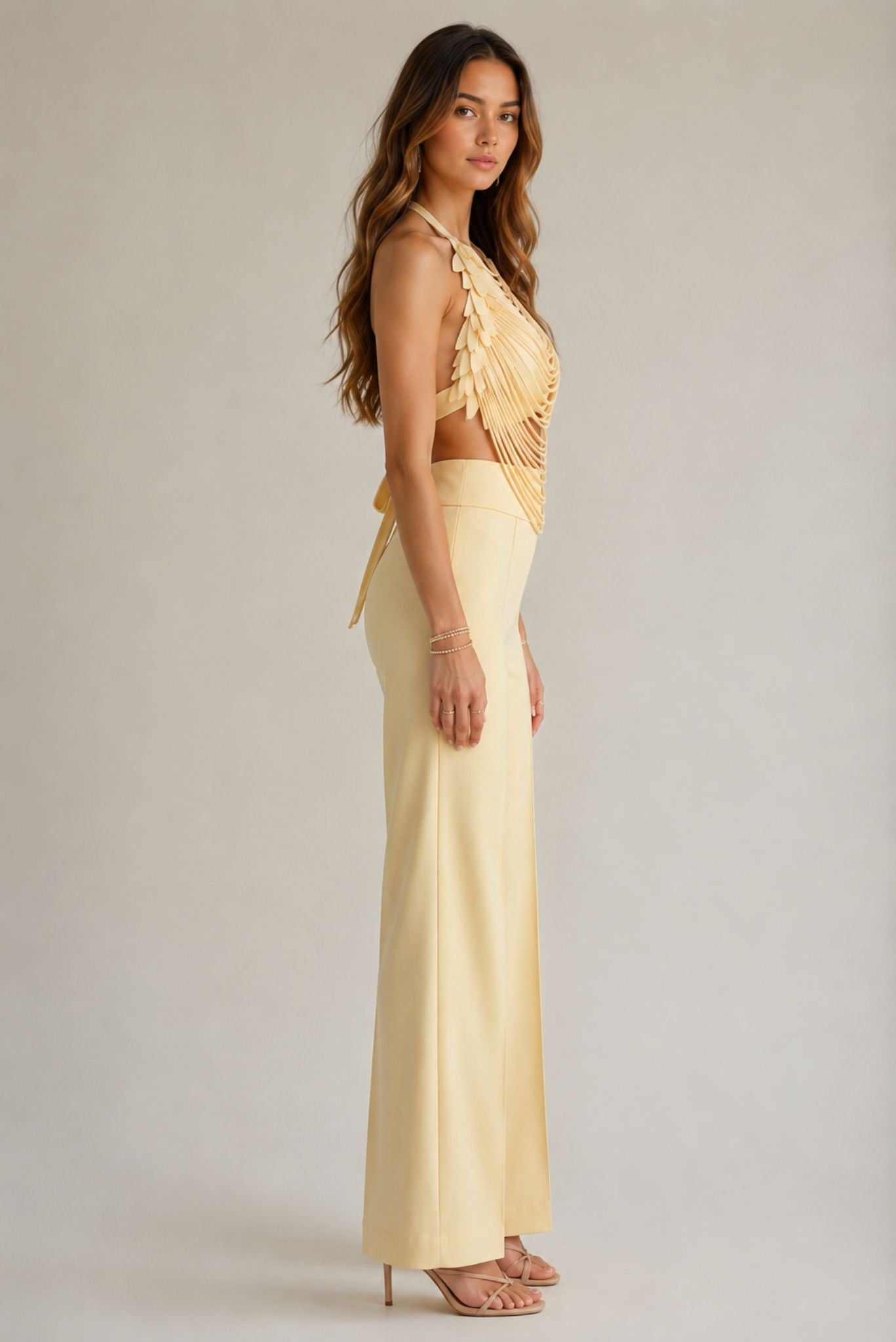 Draped petal halter top in light yellow with layered chain-like detailing, worn with matching pants