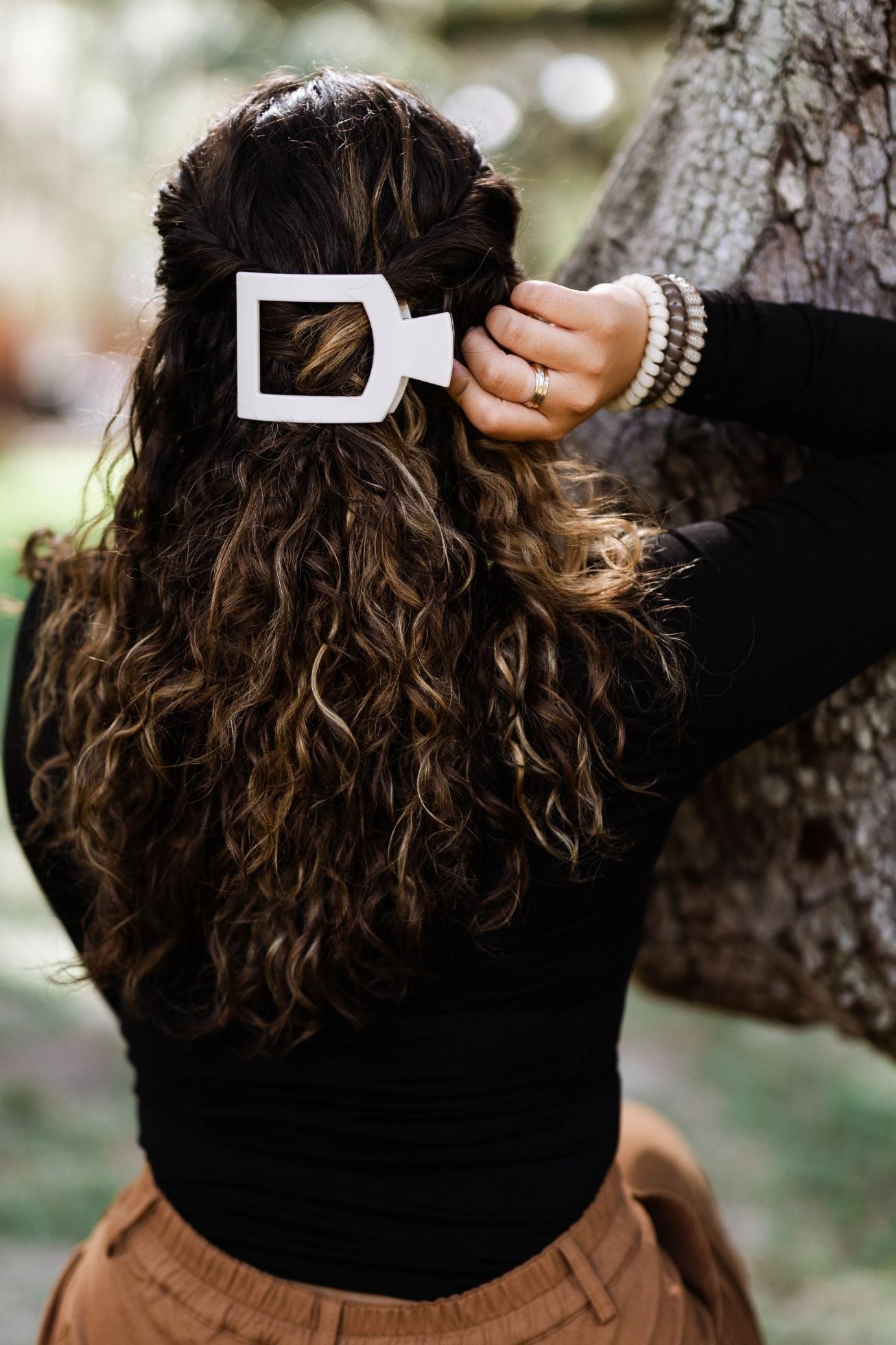 Small flat square hair clip securing dark wavy hair on the side, cream finish