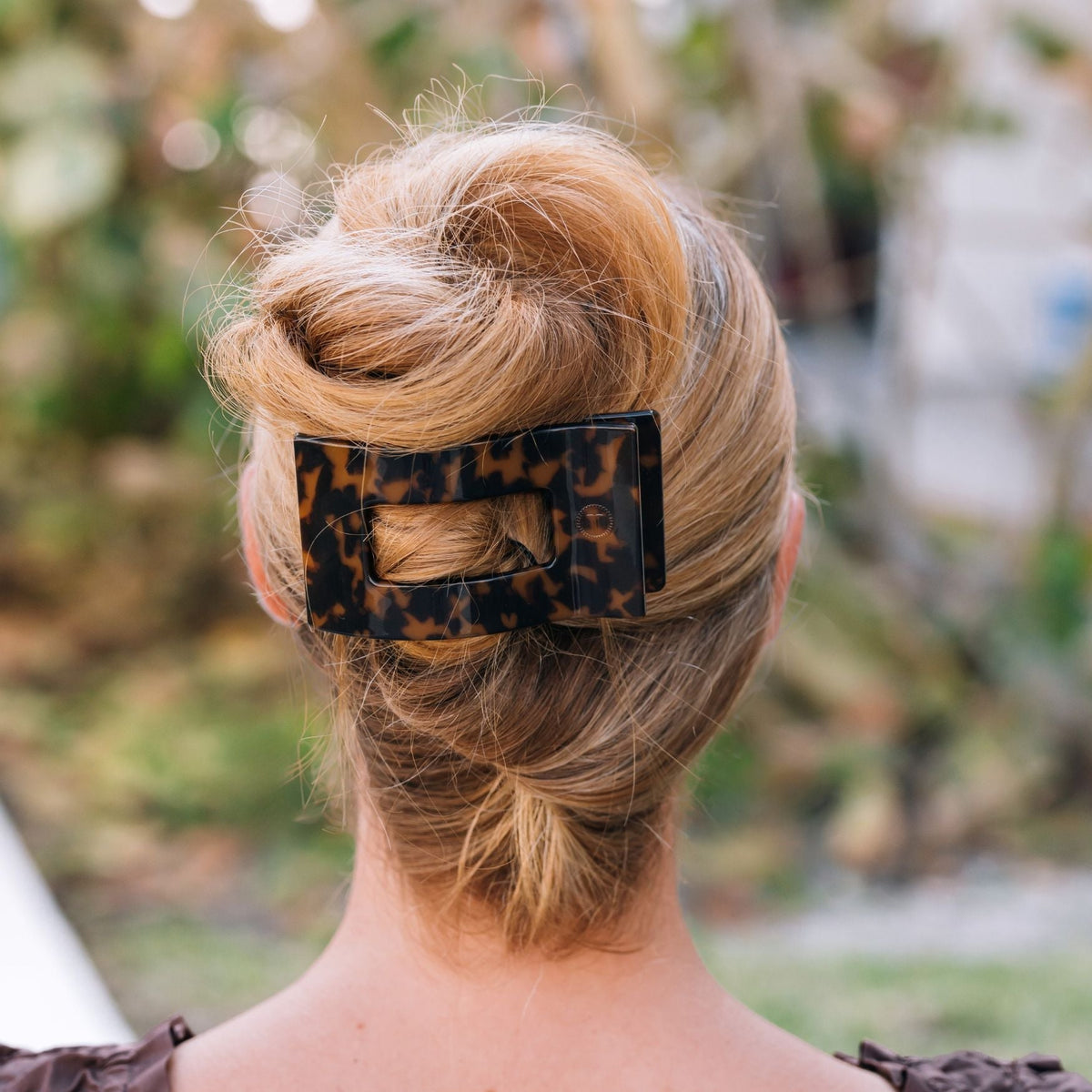 Tortoise shell rectangular hair clip holding a low bun hairstyle