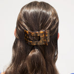Tortoise shell flat rectangle hair clip securing dark hair