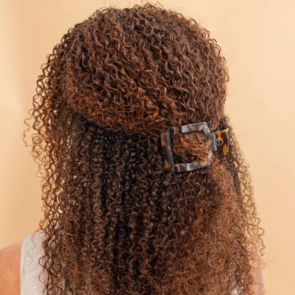 Tortoiseshell square hair clip holding curly hair back, flat design