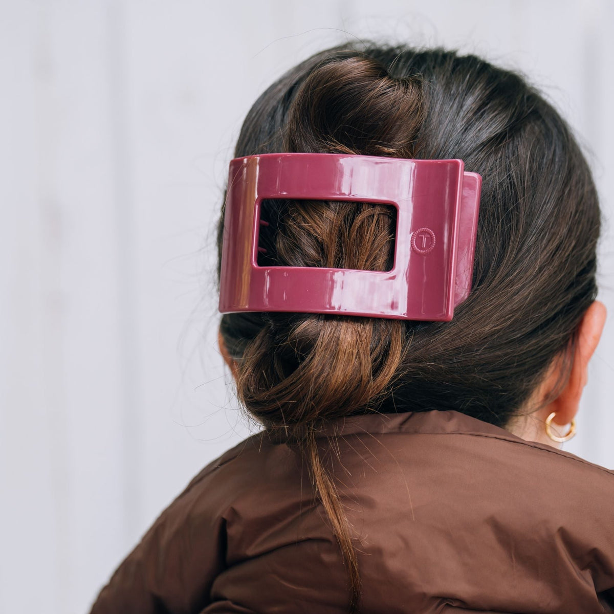 Maroon rectangular hair clip holding dark hair at the back