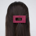 Small flat rectangle hair clip, magenta, clipped on dark hair