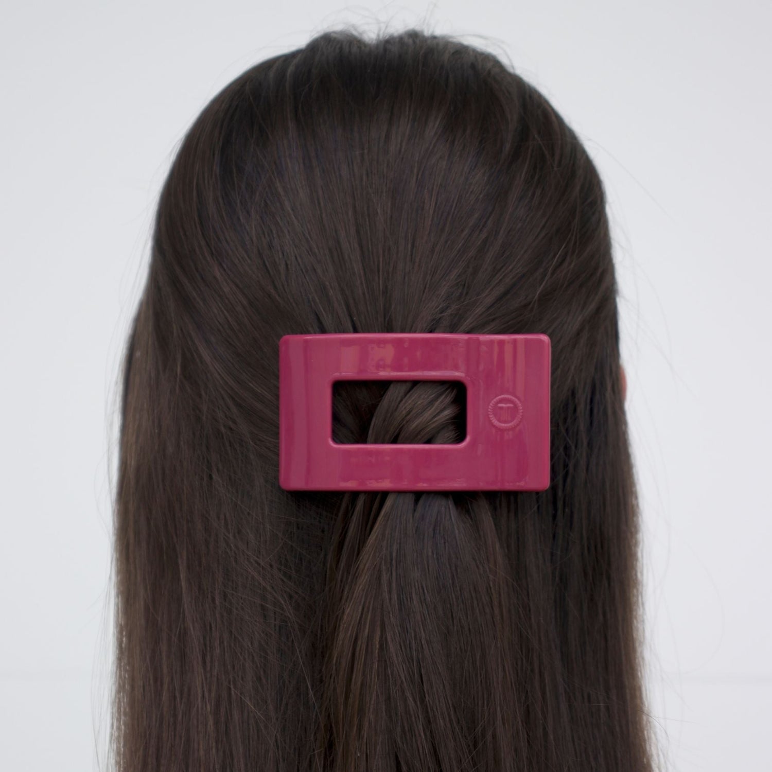 Small flat rectangle hair clip, magenta, clipped on dark hair