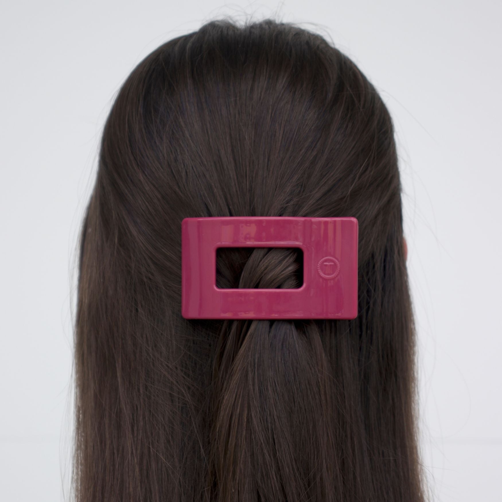 Small flat rectangle hair clip, magenta, clipped on dark hair